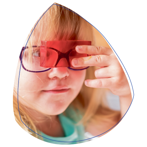 Ein Mädchen mit Brille schaut durch ein rotes Glas.