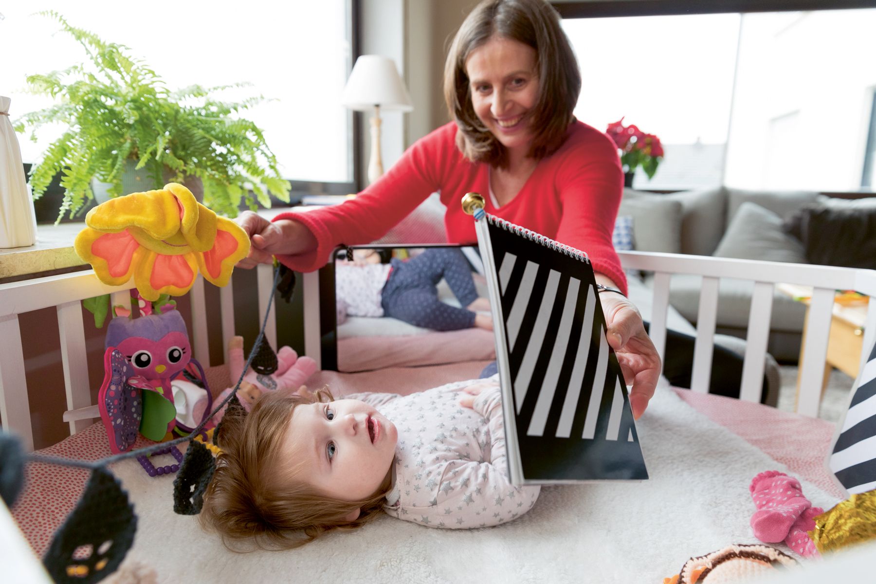 Maria Wiesner fördert die kleine Ismini, die in ihrem Tagesbett liegt, mit visuellen Reizen.