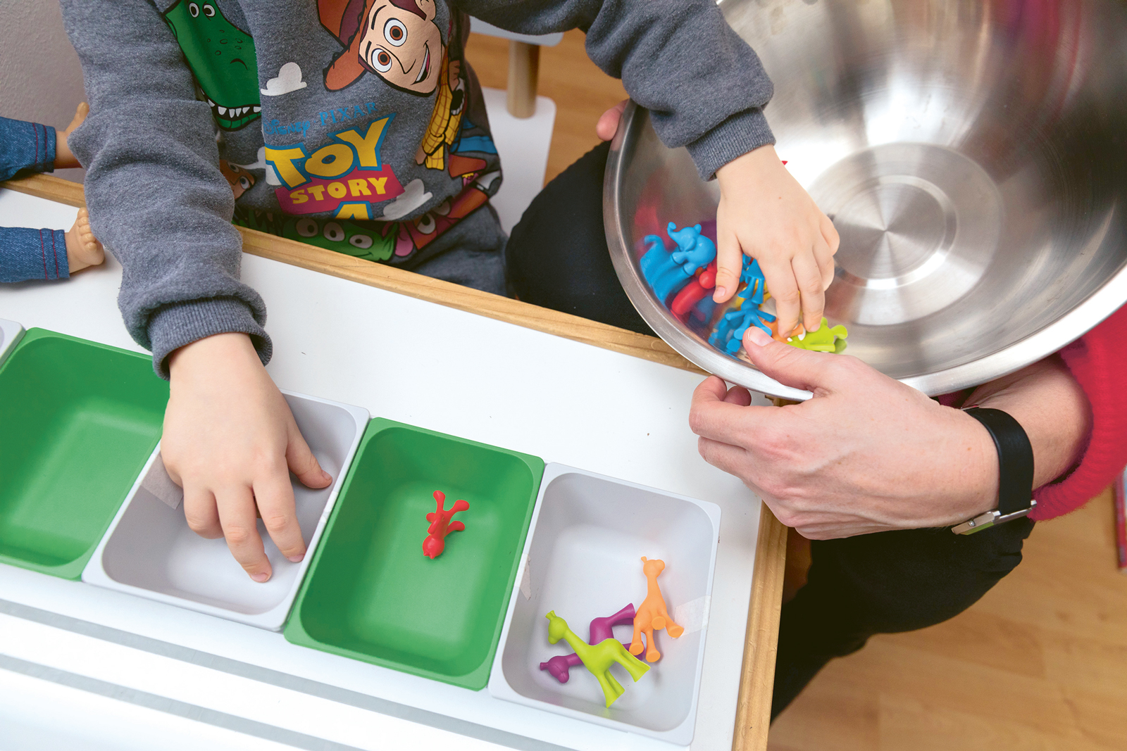 Maks sortiert bunte Plastikfiguren in gleichgroße Kästchen.