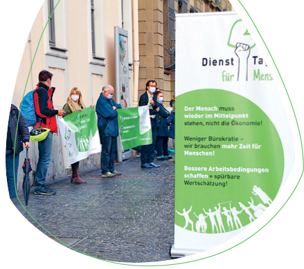 Dieses Bild zeigt die Vertreterinnen und Vertreter des Bündnisses "Dienst-Tag für Menschen", die vor dem Würzburger Juliusspital demonstrieren.