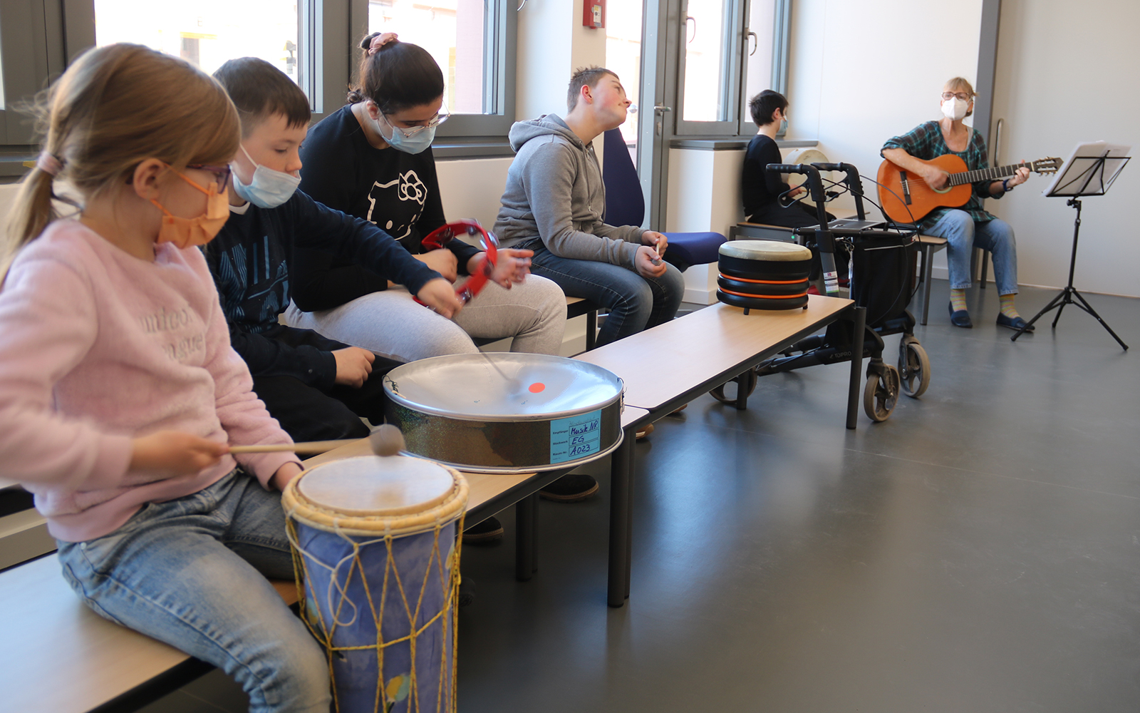 Kinder musizieren gemeinsam mit Trommeln und Schellenringen.