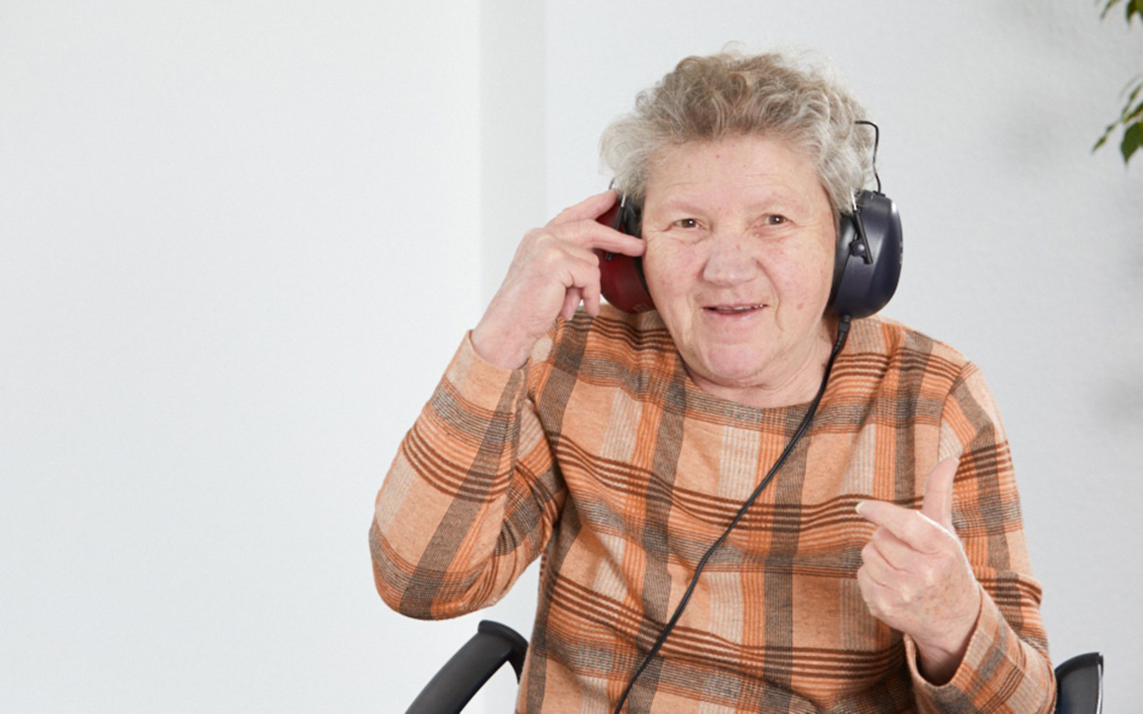 Eine Seniorin welche Kopfhörer auf hat.