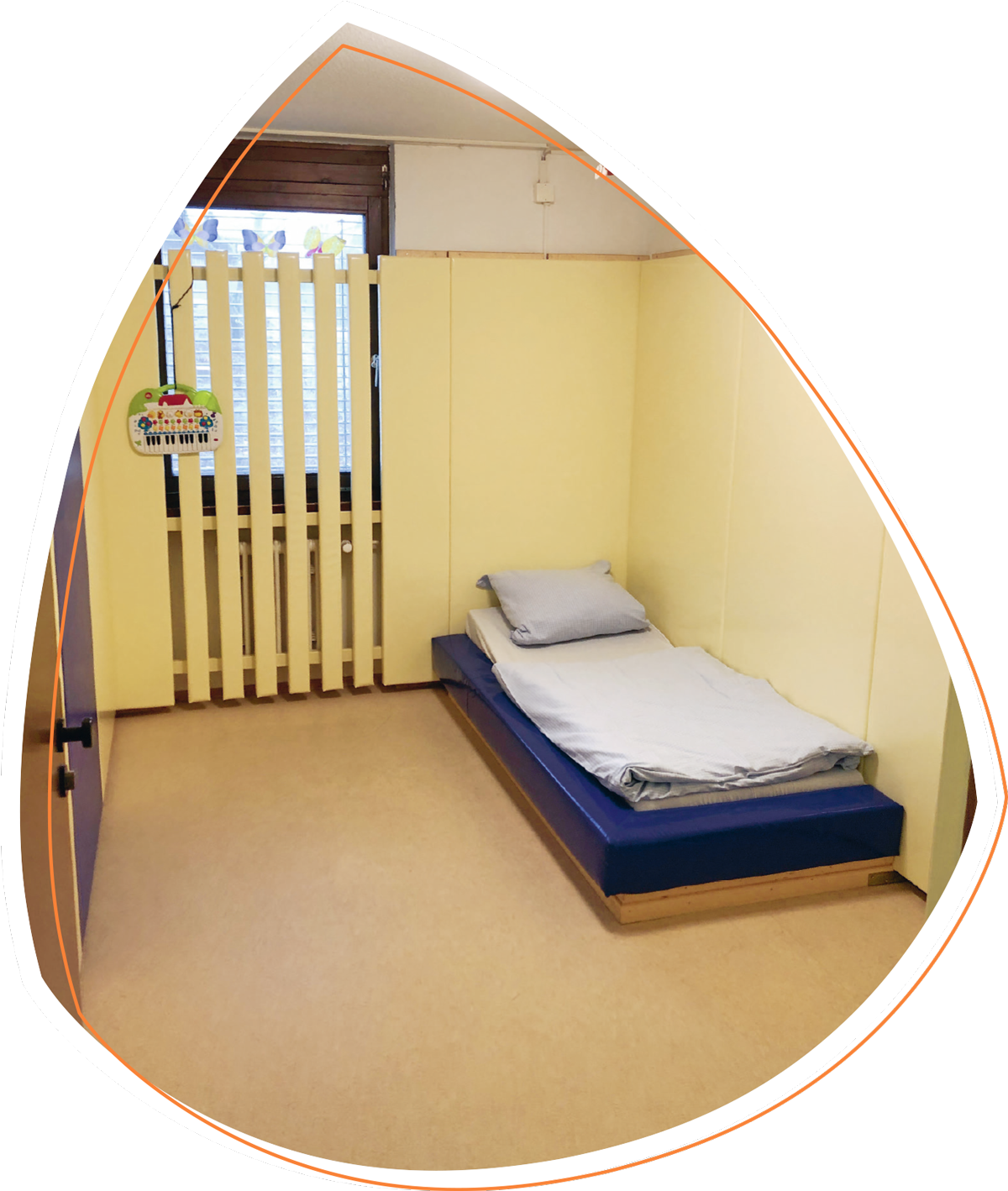 In Adeas Zimmer steht in der rechten Ecke ein Bett. Ansonsten sind keine Einrichtungsgegenstände zu erkennen. Das Bett und die cremefarbigen Wände sind dick gepolstert.