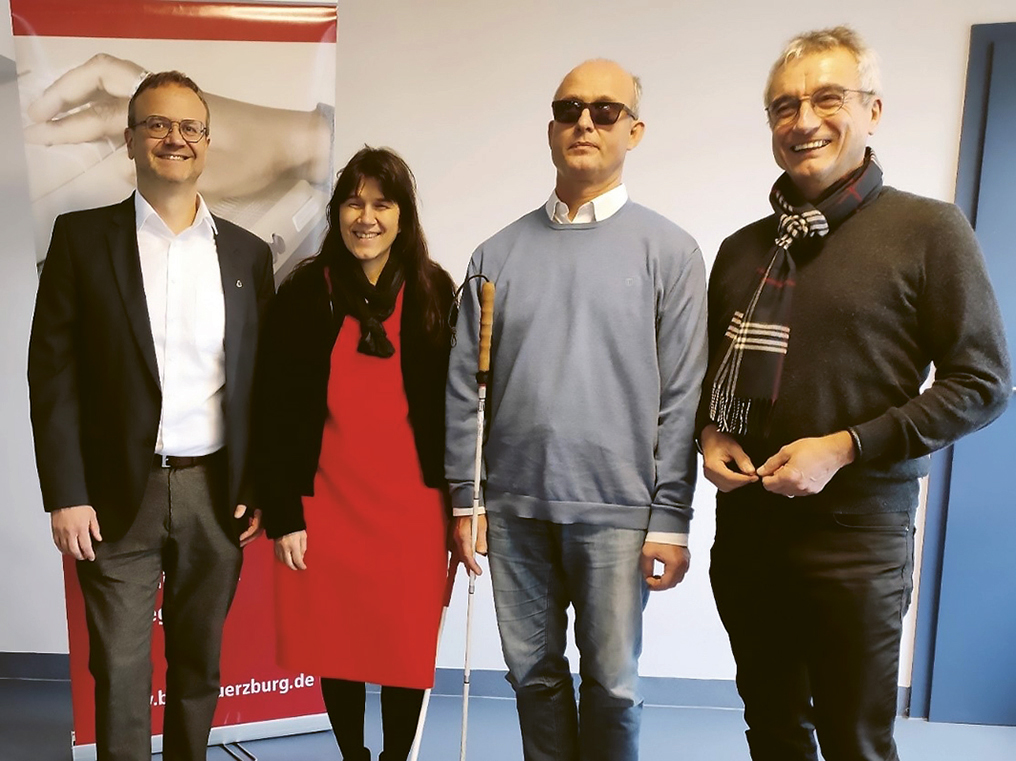 Der neue Aufsichtsrat der BFW Würzburg. Von links Dr. Marco Bambach, Judith Faltl (Geschäftsführerin BFW Würzburg), Frank Schäfer, Dieter Feser. Frank Schäfer trägt eine schwarze Sonnenbrille und trägt einen Langstock bei sich.