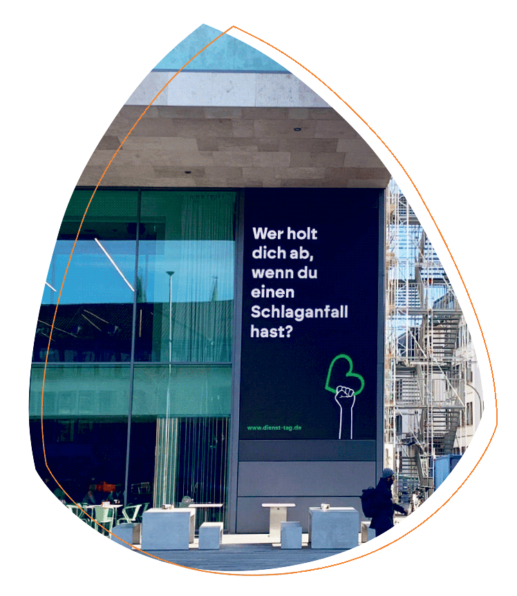 Eine Werbetafel zeigt ein Plakat der Kampagne „zappenduster“ mit schwarzem Hintergrund und weißer Schrift: „Wer holt dich ab, wenn du einen Schlaganfall hast?". Die Tafel hängt am Mainfranken Theater in Würzburg.