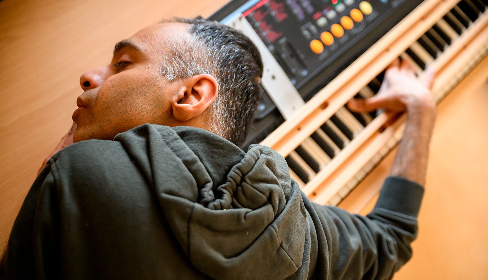 Der taubblinde Chinu Kirloskar drückt Tasten an einem Keyboard und legt den Kopf nahe an die Tasten, um die Töne als Vibrationen wahrzunehmen.