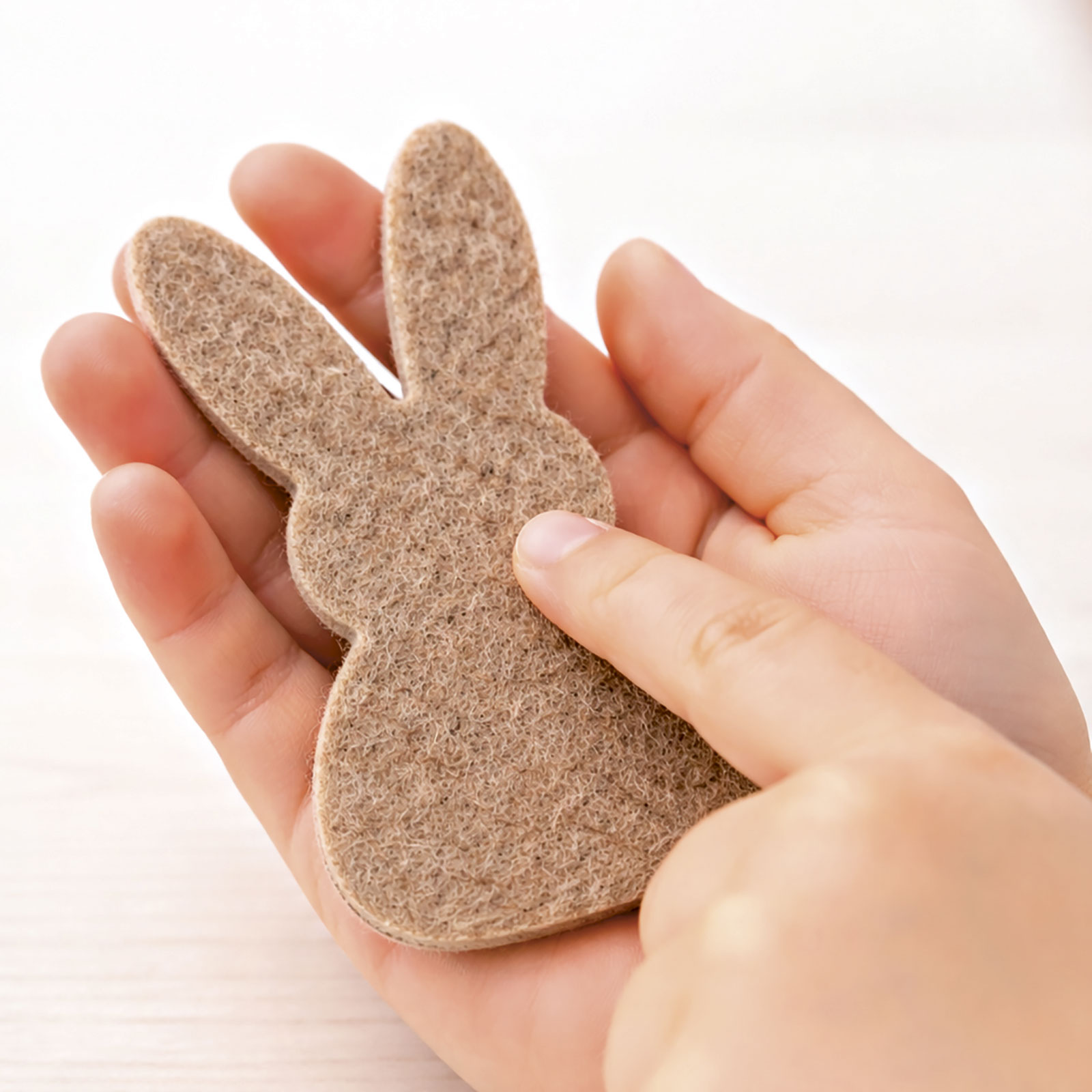 Eine Hand ertastet ein kleines Filzobjekt in Hasenform.