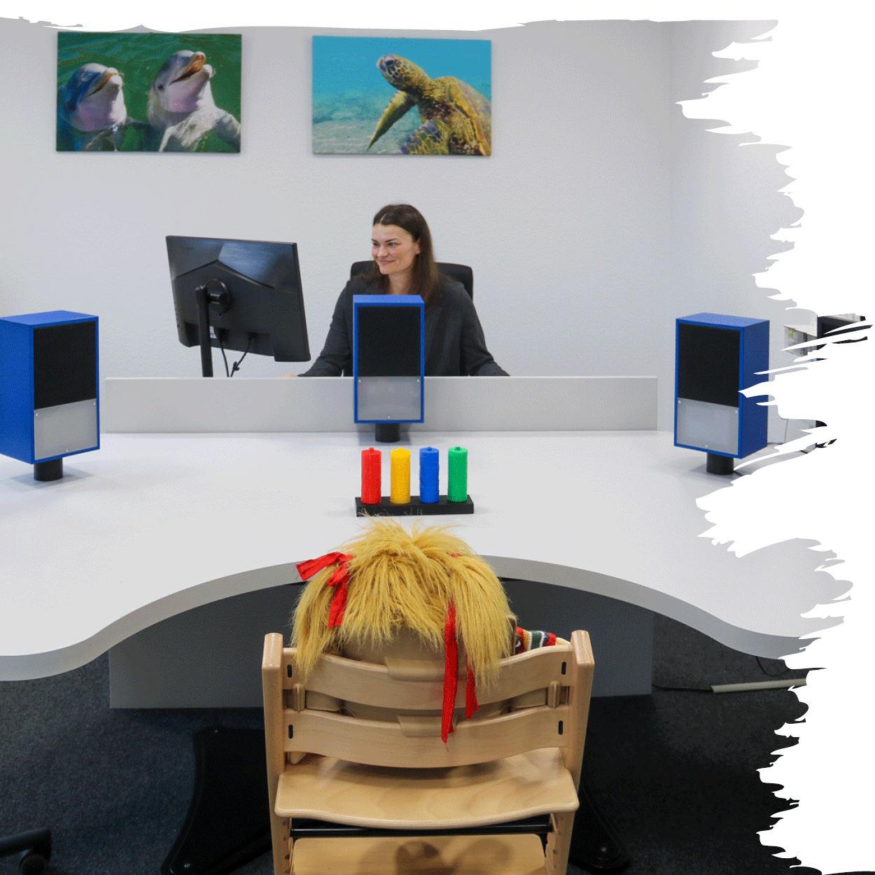 Projektmitarbeiterin Elena Meuser sitzt im Diagnostikraum des Blindeninstituts Würzburg an einem Tisch mit Monitor und Lautsprechern für Hör- und Sehscreenings.