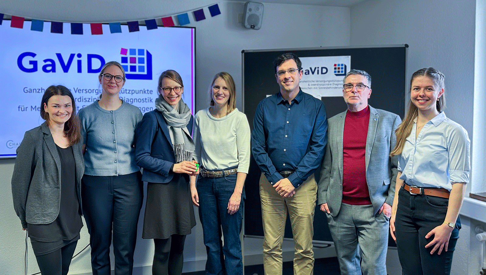 Sieben Projektbeteiligte stehen in einem Raum vor einem Bildschirm mit GaViD-Logo: Elena Meuser, Melissa Glomb, Dr. Tabea Sadowski, Dr. Sophie Flandin, Dr. Christoph Kalantari, Johannes Spielmann und Anastasia Kov