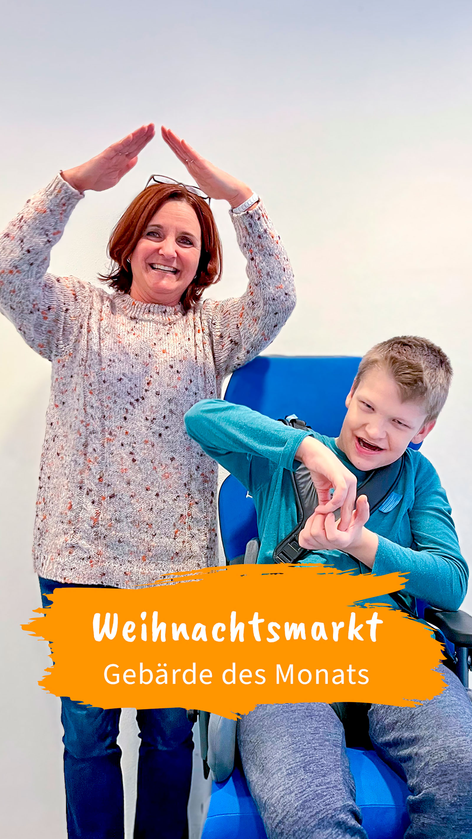 Eine Frau steht neben einem Jungen, der in einem Stuhl sitzt; beide führen eine Gebärde aus. Text im Bild: „Weihnachtsmarkt – Gebärde des Monats“.