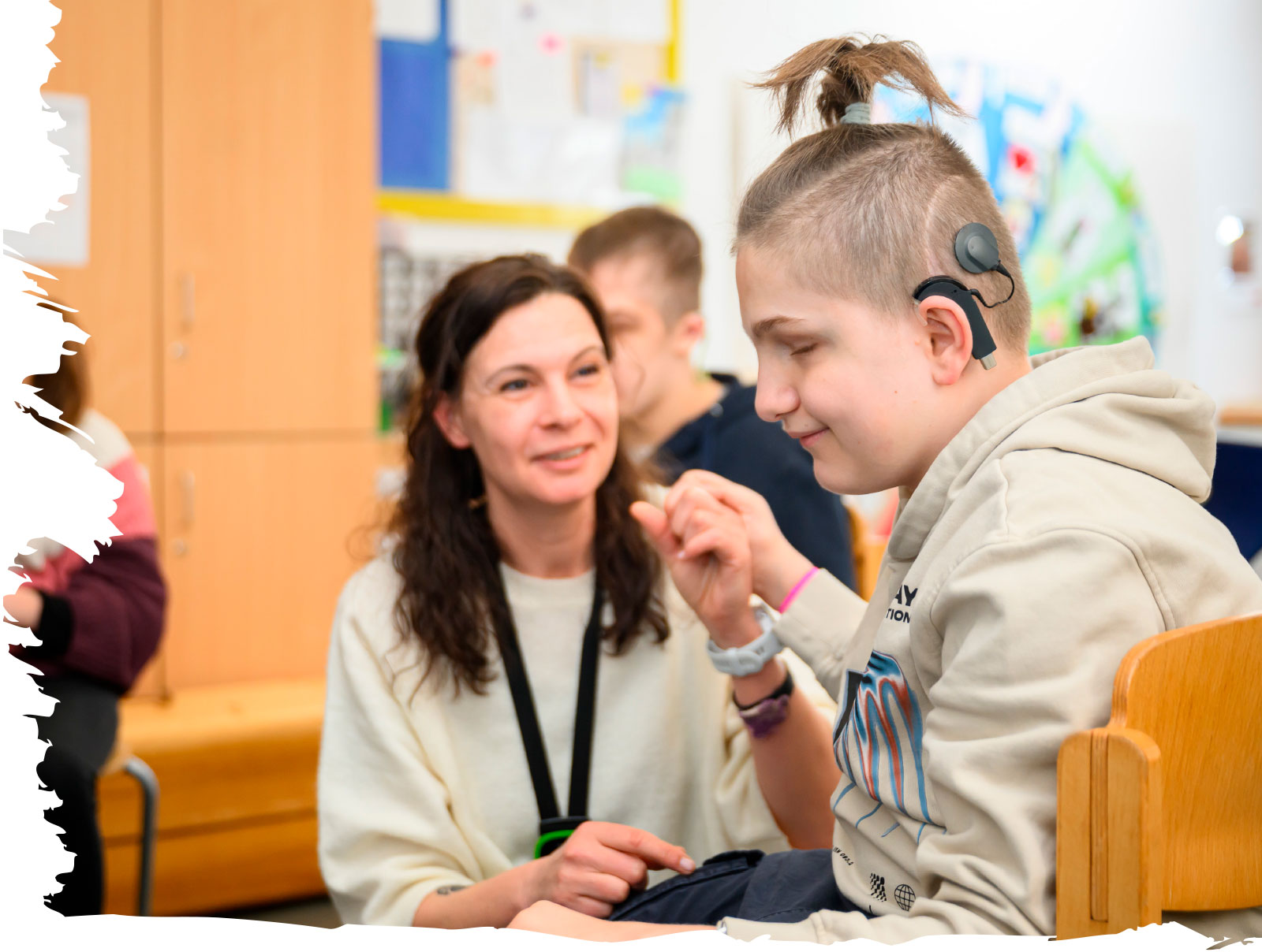 Lehrerin Anja Dantinger sitzt Lucas gegenüber. Er berührt ihre Hand beim Begrüßungsritual im Morgenkreis und nutzt dabei taktile Kommunikation.