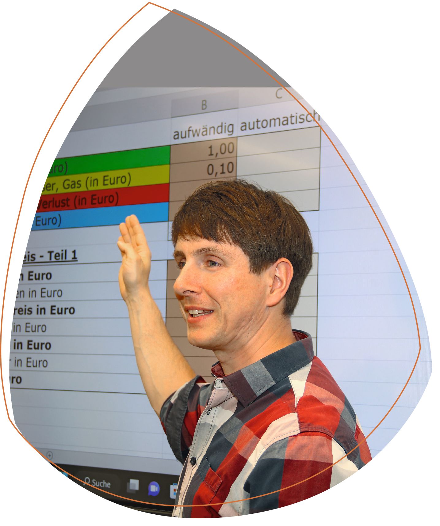 Klassenlehrer Tobias Rehnolt, der auf die Tafel zeigt. Auf dieser werden die Inhalte einer Excel-Liste projiziert. Er trägt ein kariertes Hemd. 