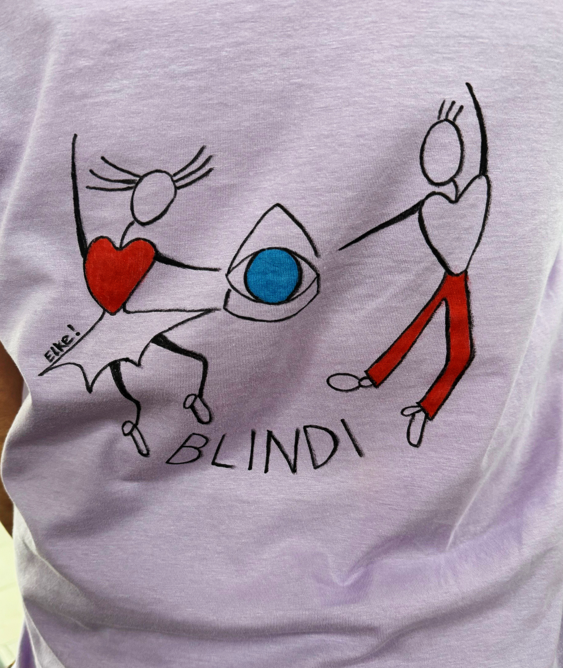 Es ist die Rückeseite einen fliederfarbenen T-Shirts zu sehen, auf das das Logo des Tanzfestes gemalt wurde. 
