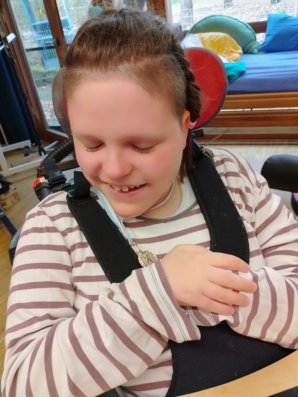 Ein freudiges Mädchen im Rollstuhl, das seine Medaille stolz in Händen hält.