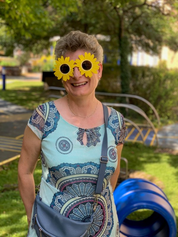 Auf dem Bild sieht man eine Frau, die eine Sonnenblumen-Sonnenbrille trägt