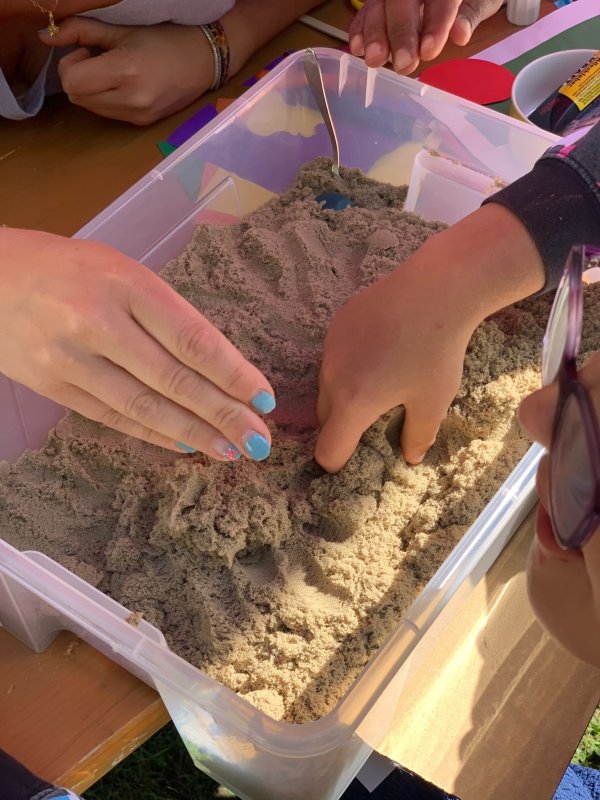 Auf dem Bild sieht man Hände, die Sand fühlen