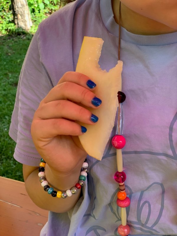 Auf dem Bild sieht man eine Hand mit blau lackierten FIngernägeln, die ein Stück HOnigmelone in der Hand hält