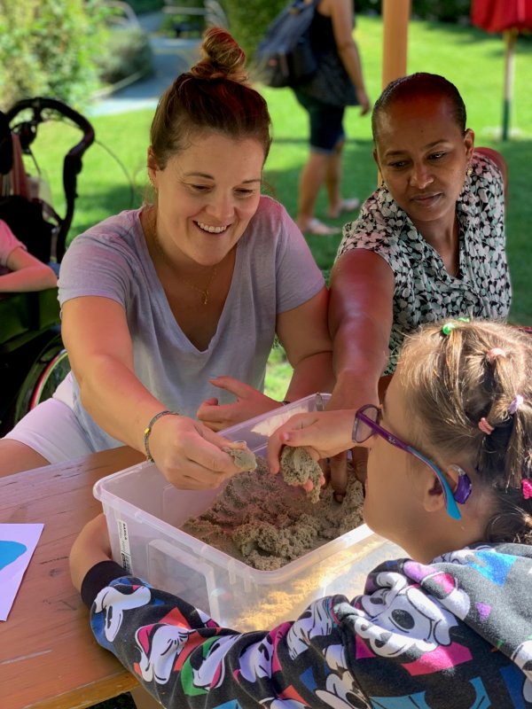 Auf dem Bild iseht man zwei Frauen und ein Mädchen, die mit ihren Händen Sand fühlen