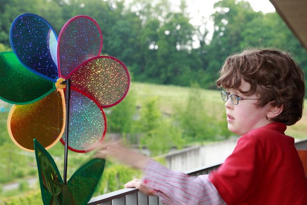 Ein Junge dreht an einer bunten Blume aus Glas