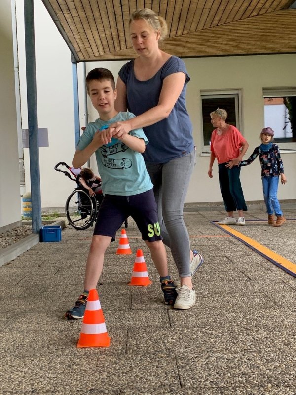 Auf dem Bild sieht man einen Jungen, der begleitet von einer Frau einen Hindernislauf macht.