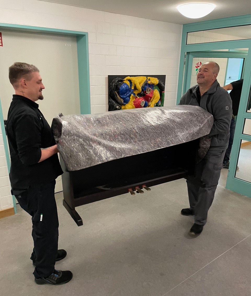 Zwei Männer tragen ein Klavier