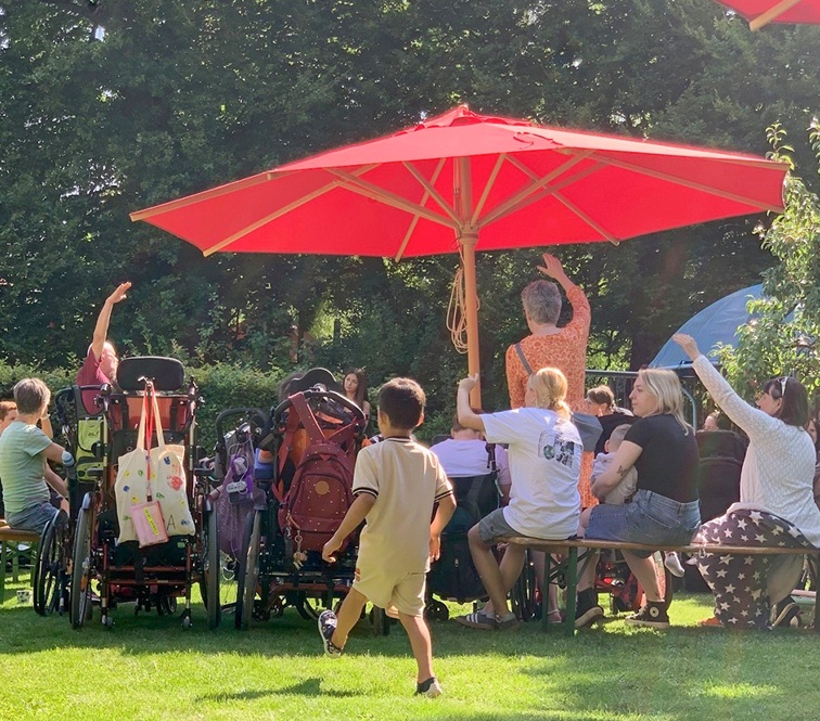 Auf dem Bild zieht man einige Zuschauer im Garten des Blindeninstituts München