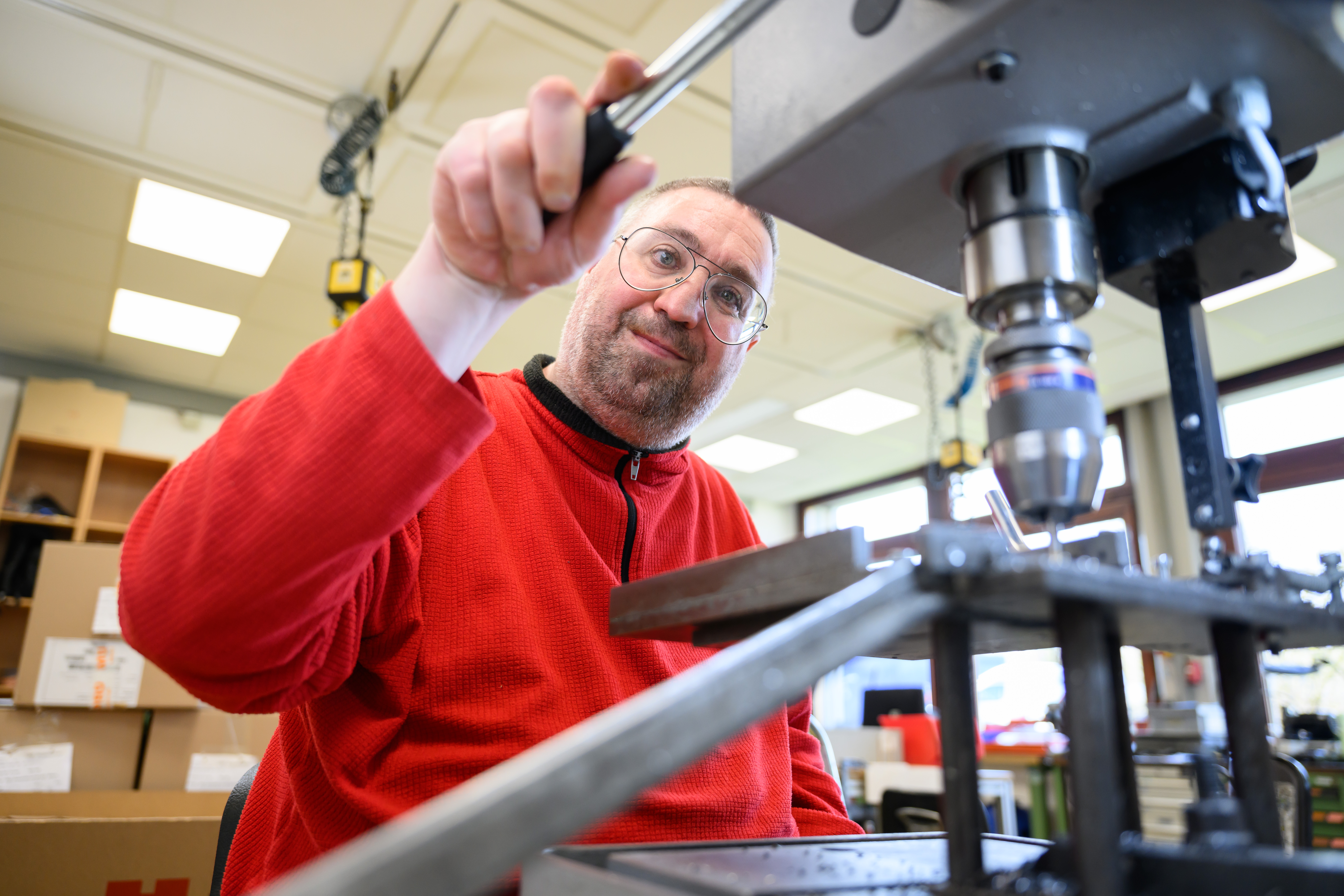 Ein Mann mit Brille schaut von oben auf den Bohrkopf einer großen Bohrmaschine im Vordergrund.