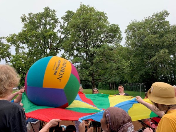 Auf dem Bild sieht man viele Köpfe, ein Schwungtuch und einen großen Ball darauf.