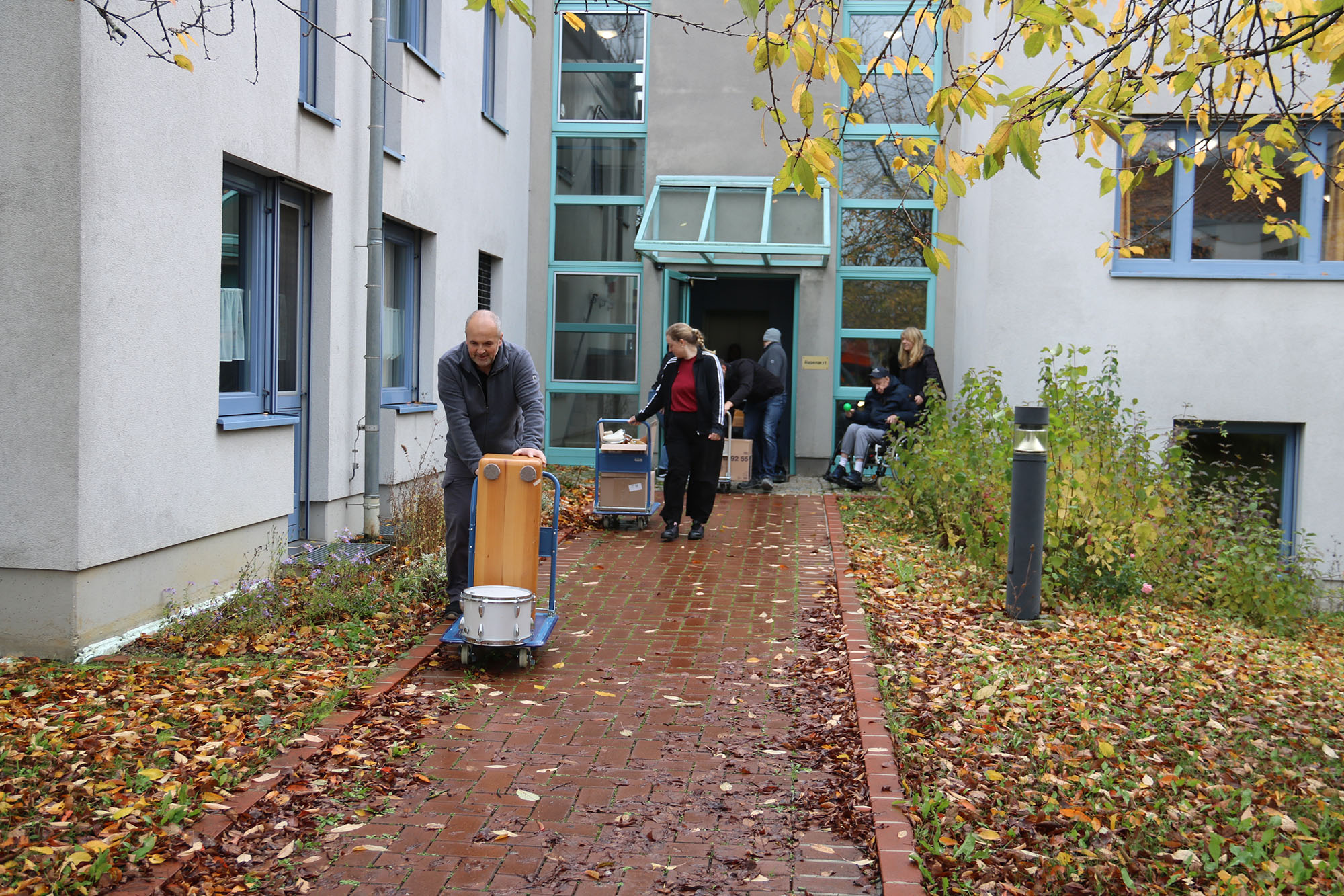 Ein Mann und eine Frau laufen auf einem Weg und schieben kleine Wagen mit Musikinstrumenten