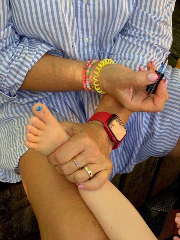 Auf dem Bild sieht man Hände und Füße mit einem blau lackiertem Nagel