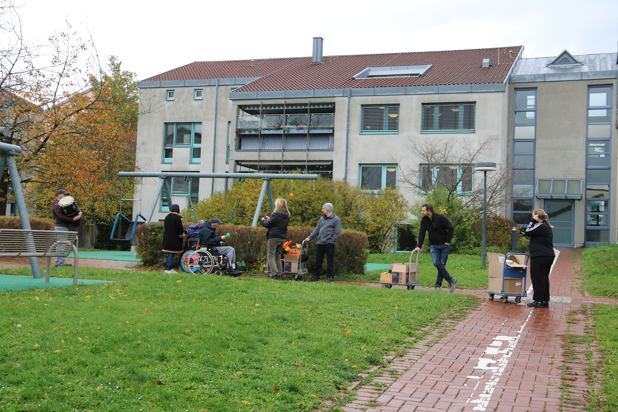Mehrer Personen laufen und fahren mit Rollstühlen hintereinander auf einem Weg