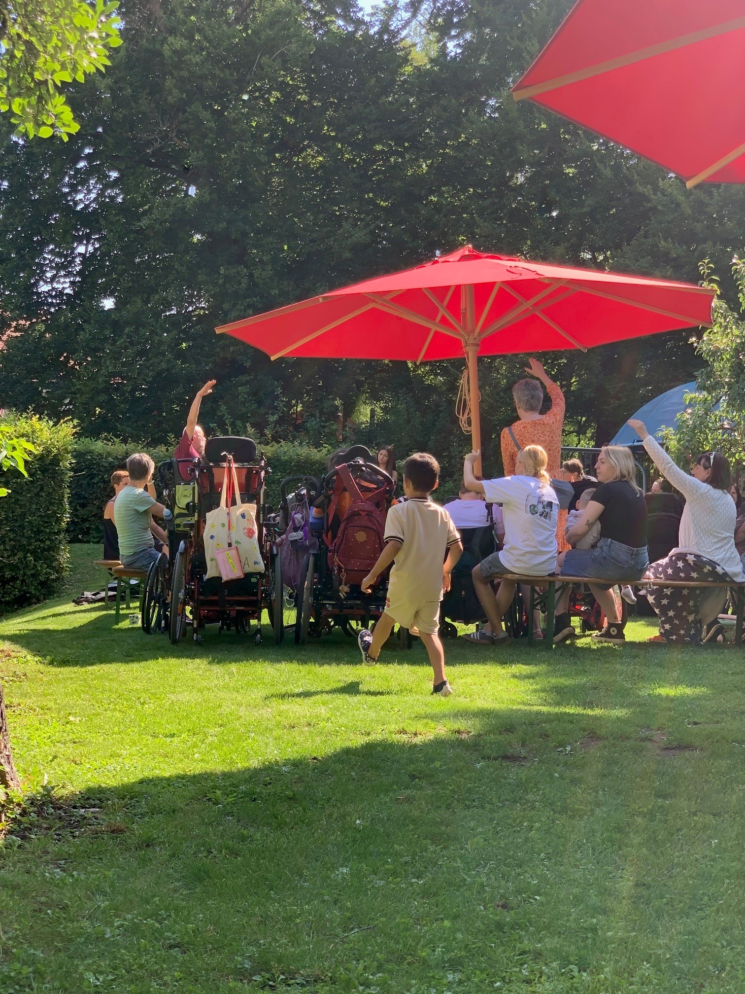 Auf dem Bild sieht man eine Gruppe von Menschen unter einem roten Sonnenschirm.