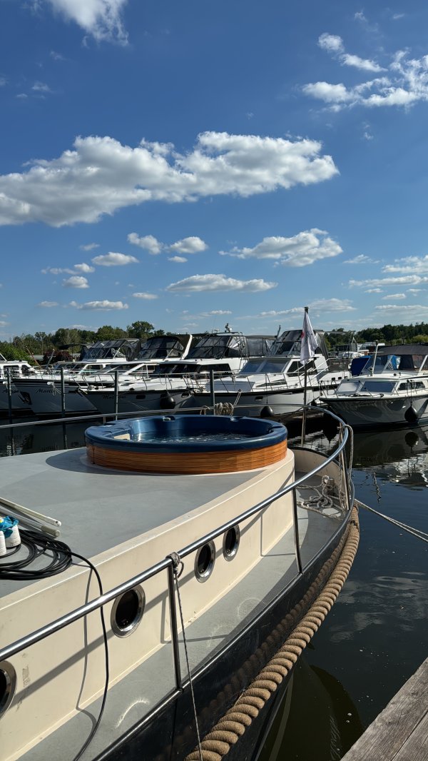 Auf dem BIld sieht man ein Hausboot. Das Wetter ist schön, es gibt ein paar Wolken.