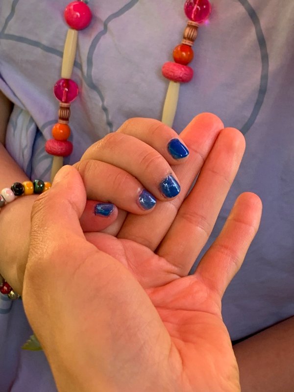 auf dem Bild sieht man eine Hand mit blau lackierten Fingernägeln