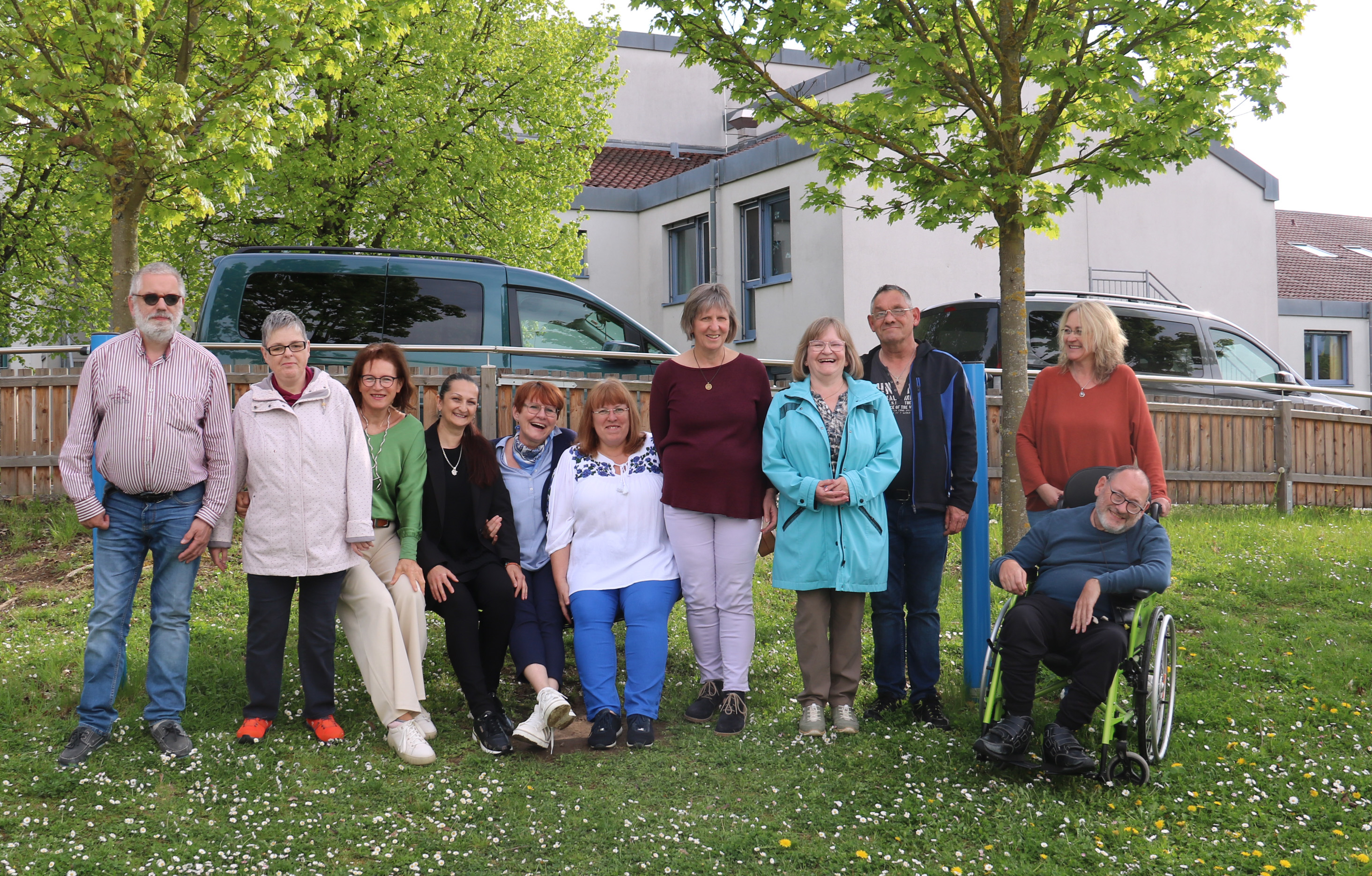 Eine Gruppe von Menschen mit und ohne Behinderung stehen auf einem Spielplatz