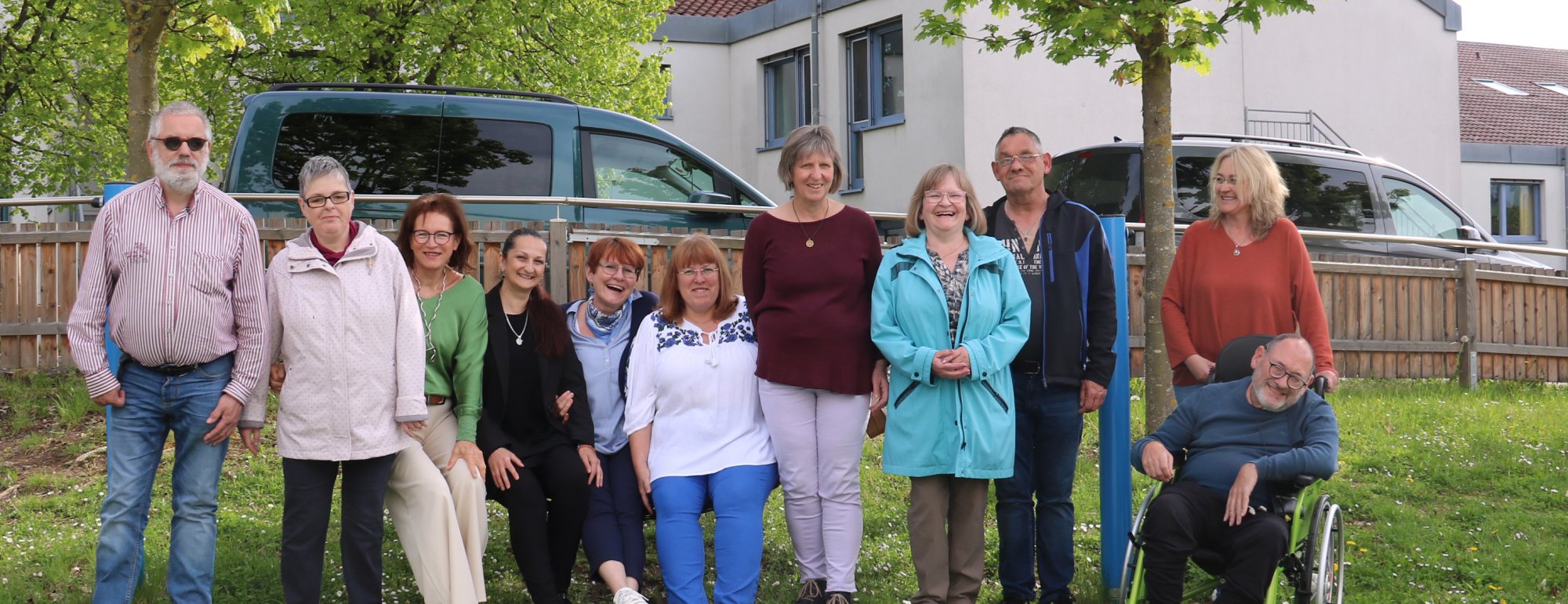 Eine Gruppe von Menschen mit und ohne Behinderung stehen auf einem Spielplatz