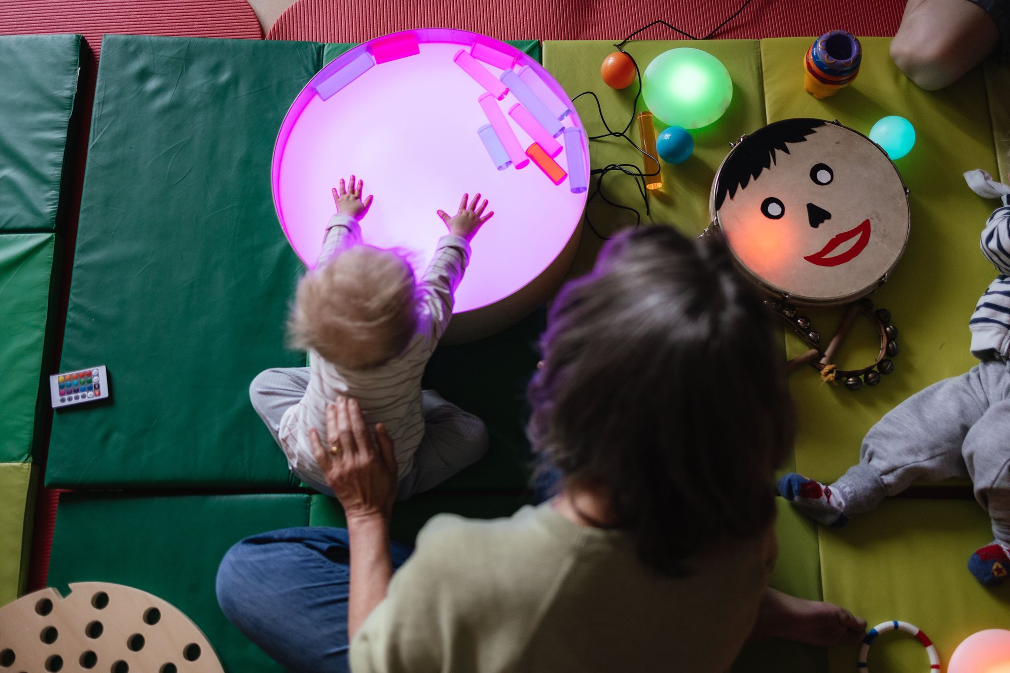 Eine Situation in der Frühförderung von oben - ein Kind spielt mit einem leuchtenden Element
