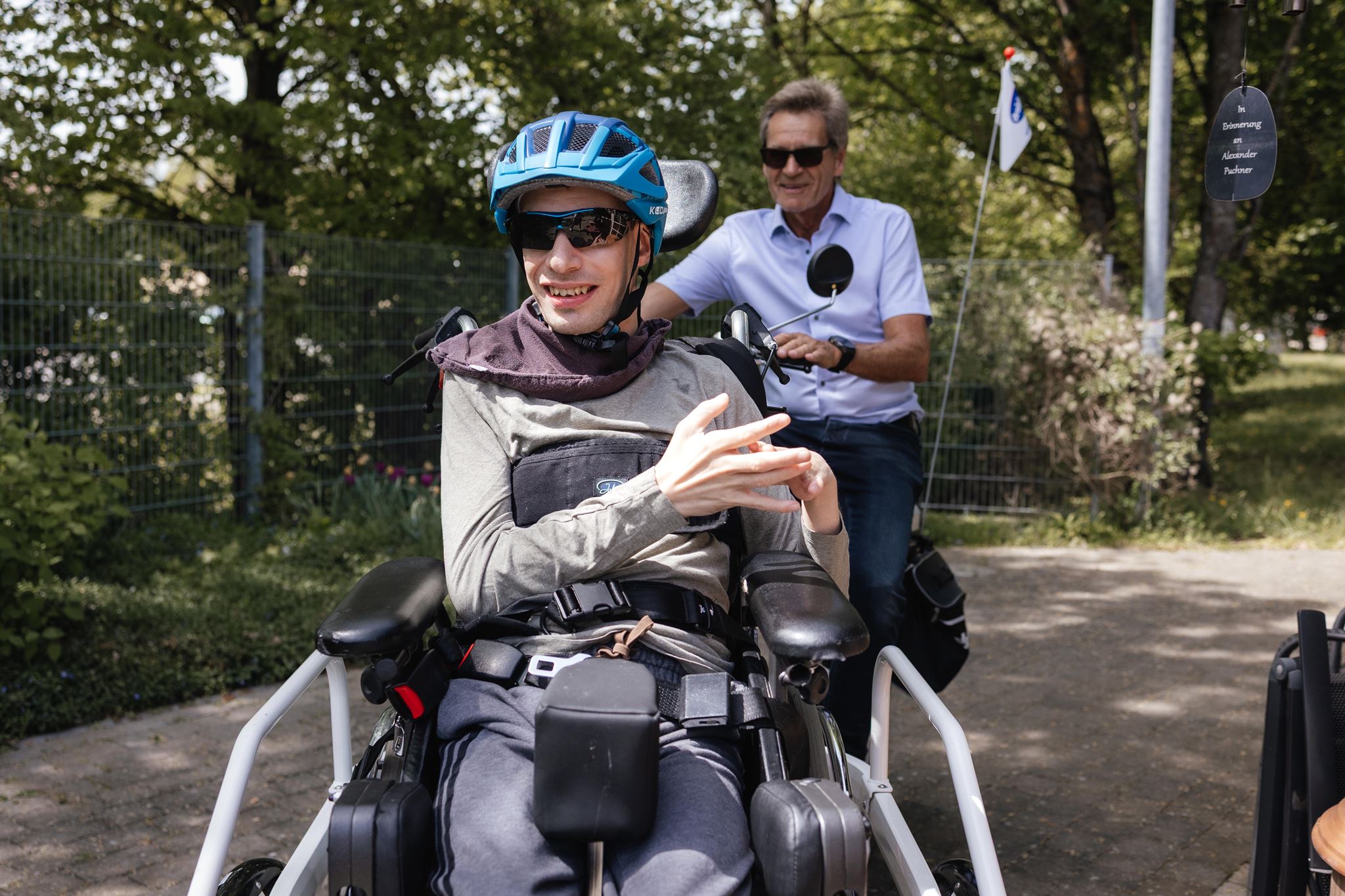 Ein Mitarbeiter fährt mit einem Bewohner in Hemau Fahrrad. Sie lachen in die Kamera.