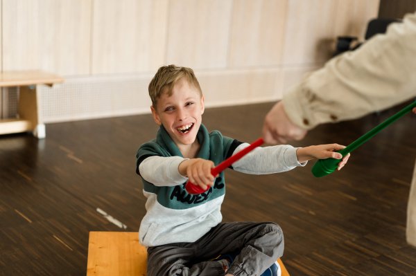 Ein Junge sitzt auf einem Rollbrett und lacht in die Kamera