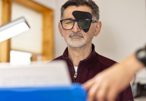 Ein Mann bei einem Augentest. Das linke Auge ist verdeckt. Er schaut konzentriert auf eine Sehtafel.