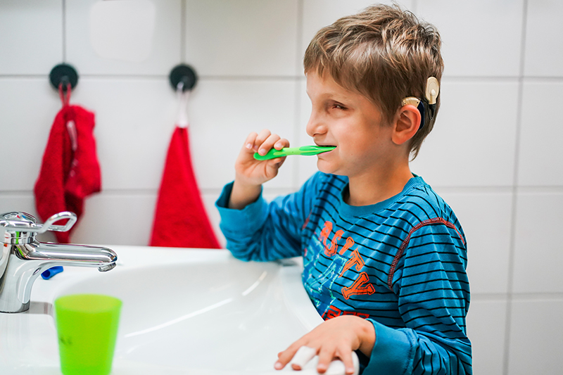 Ein Junge steht am Waschbecken und putzt sich die Zähne