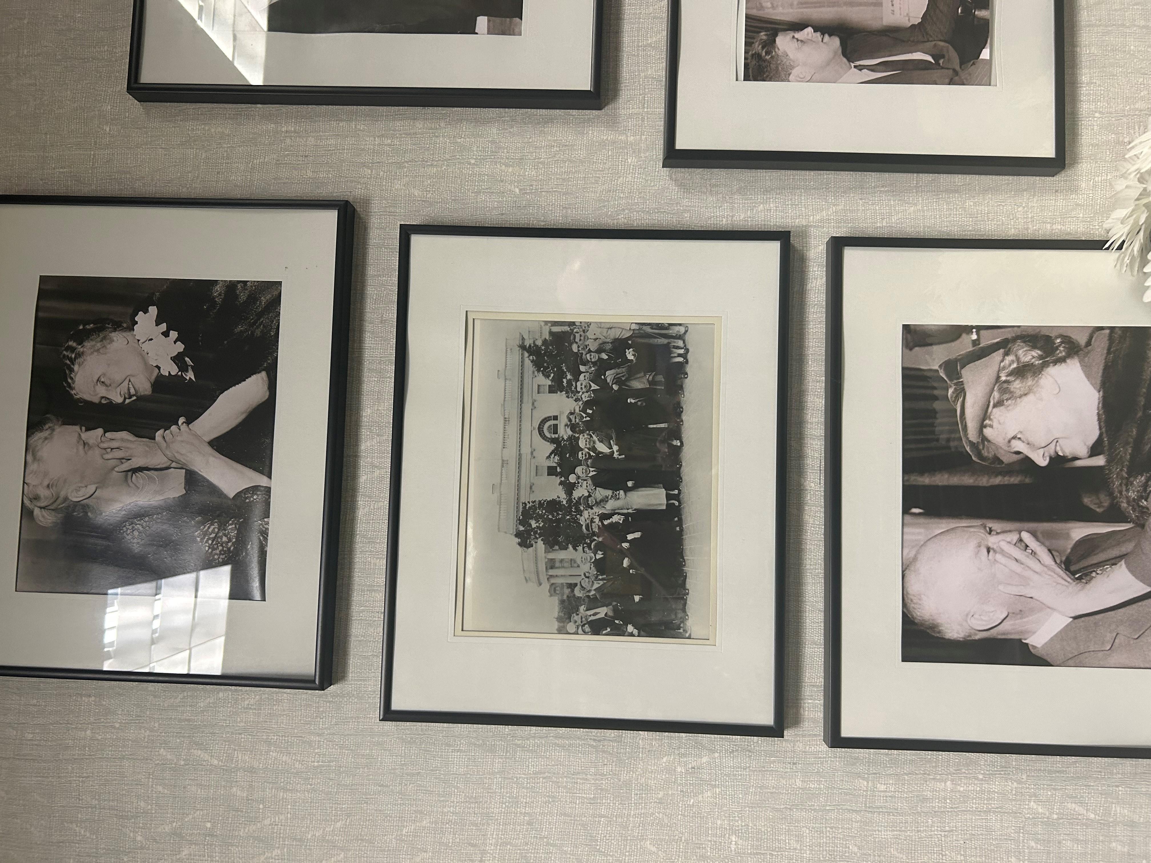 An einer Wand sind schwarz-weiß Fotoaufnahmen in Bilderrahmen angebracht.