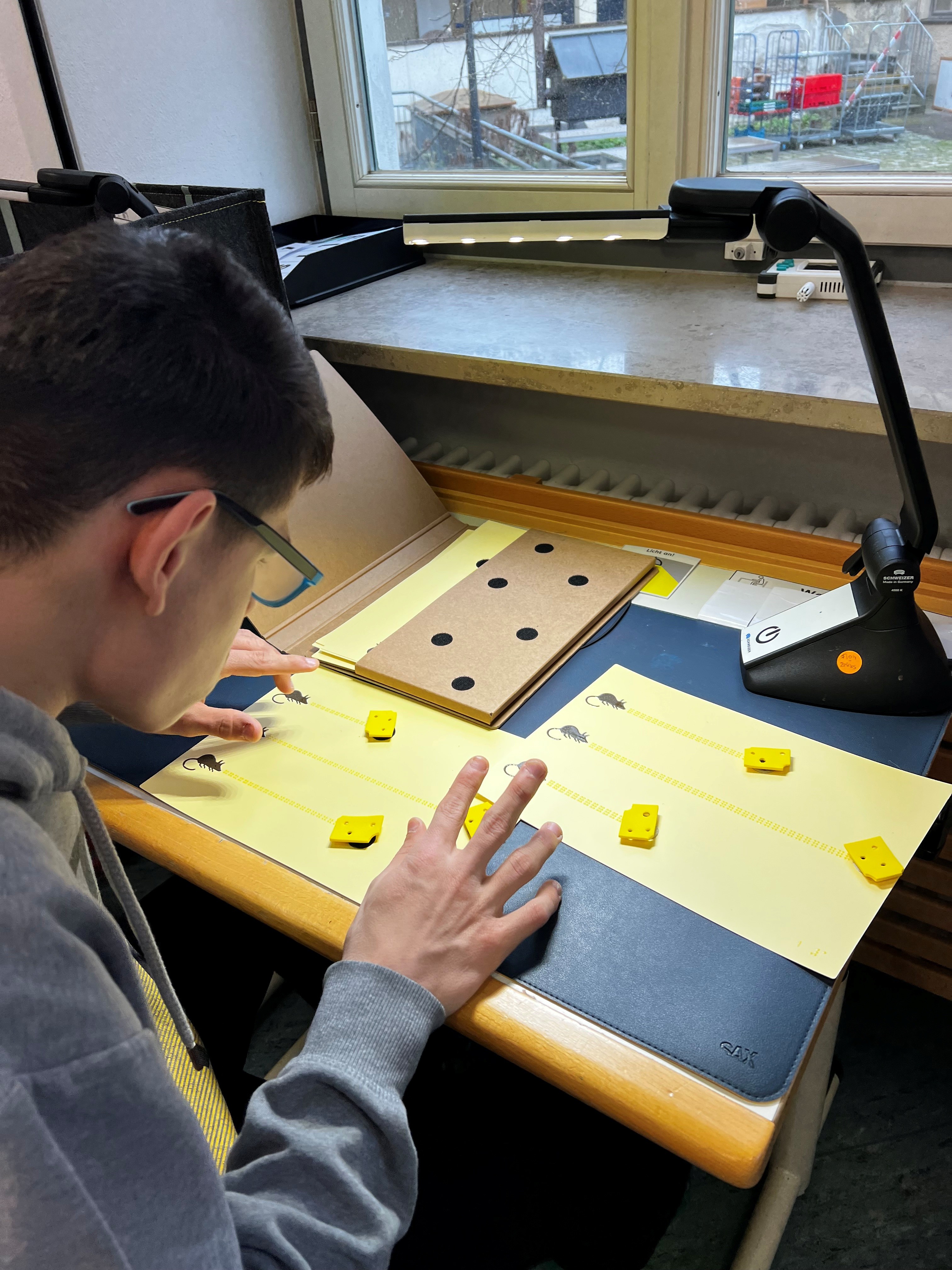 Auf dem Bild sieht man einen Jungen, der mit Brailleschrift liest