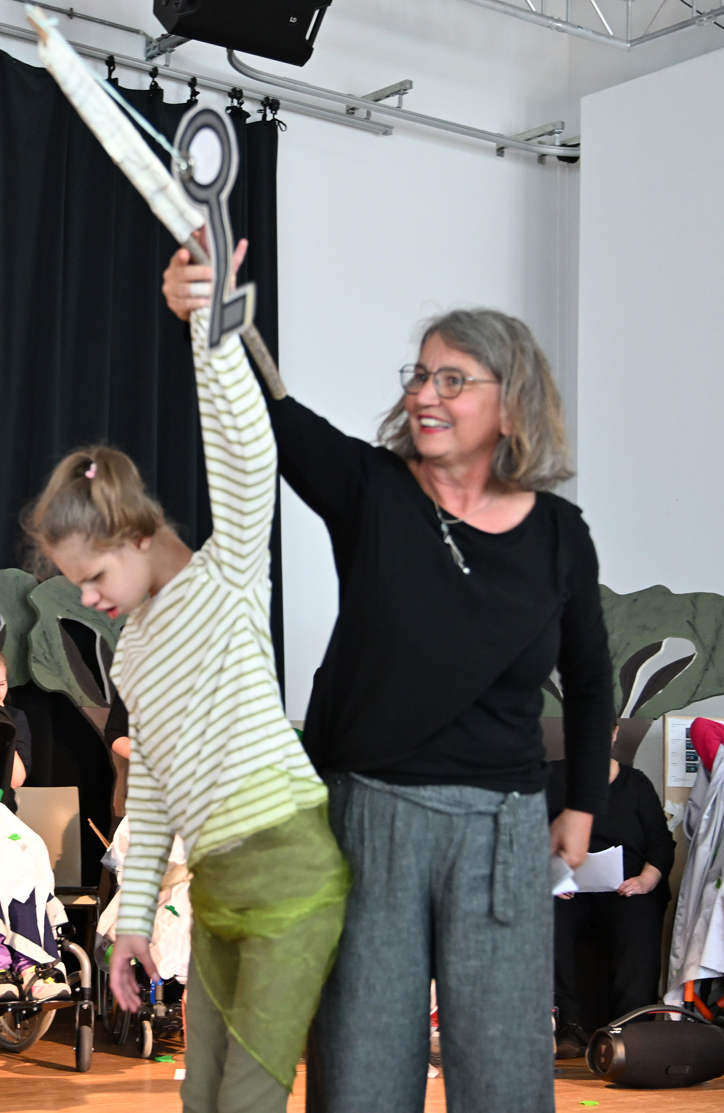 Auf dem Bild sieht man eine Frau und ein Mädchen, die beide einen Arm hochhalten.