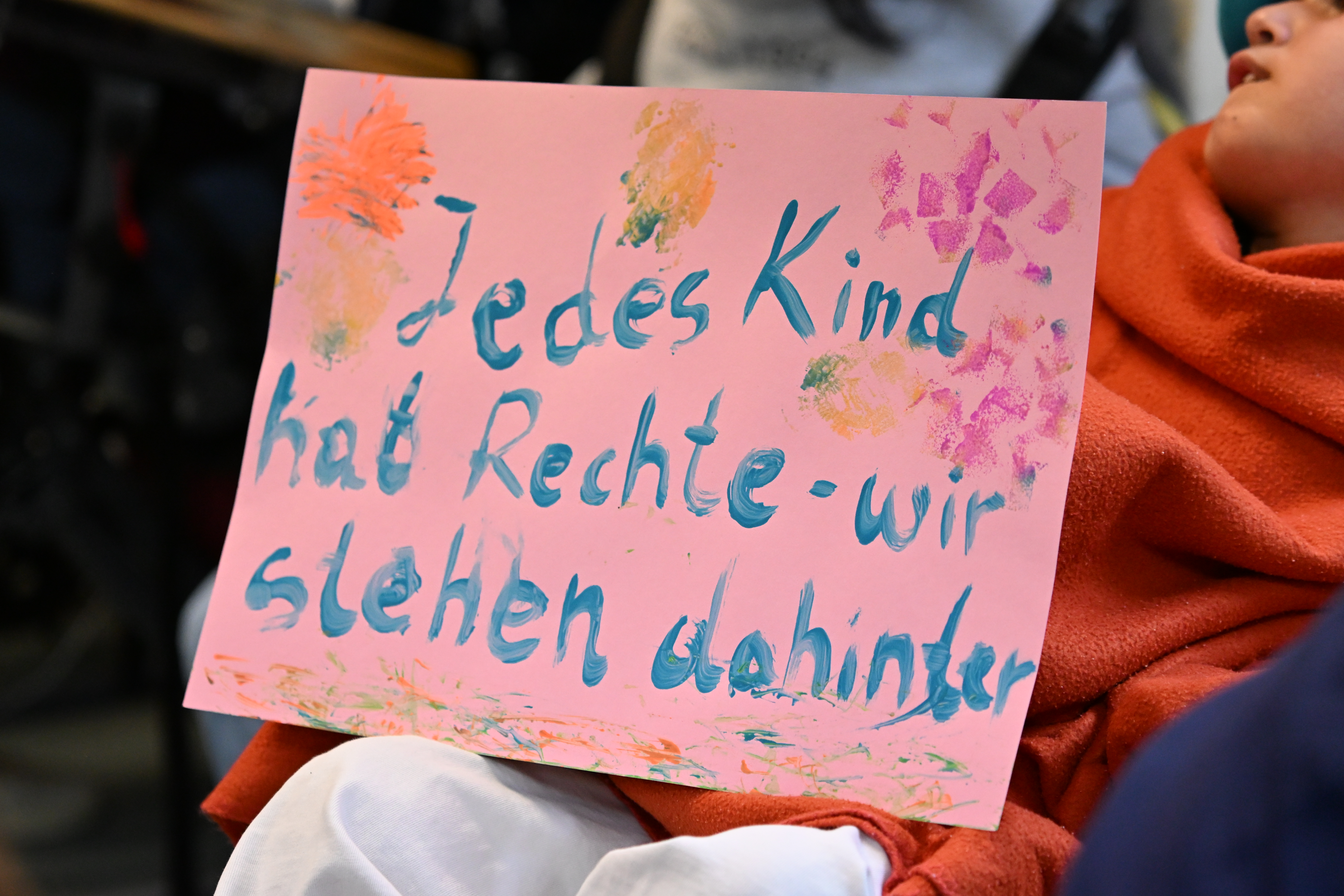 Auf dem Bild ist ein selbstgemaltes Schild zu sehen auf dem steht: Jedes Kind hat Rechte - wir stehen dahinter