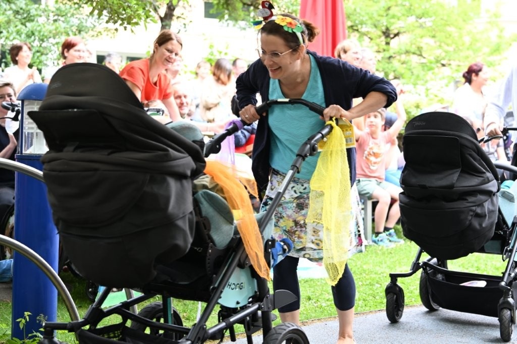 Auf dem Bild sieht man eine Frau im Kostüm, die einen Kinderwagen schiebt
