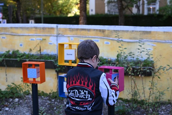 auf dem Foto sieht man einen Jungen, der an den Wortwürfeln beim Mehrsinnes-infomationspfad spielt