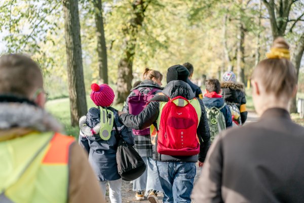 Eine Gruppe von Kindern und Erwachsenen macht einen Ausflug in den Wald.