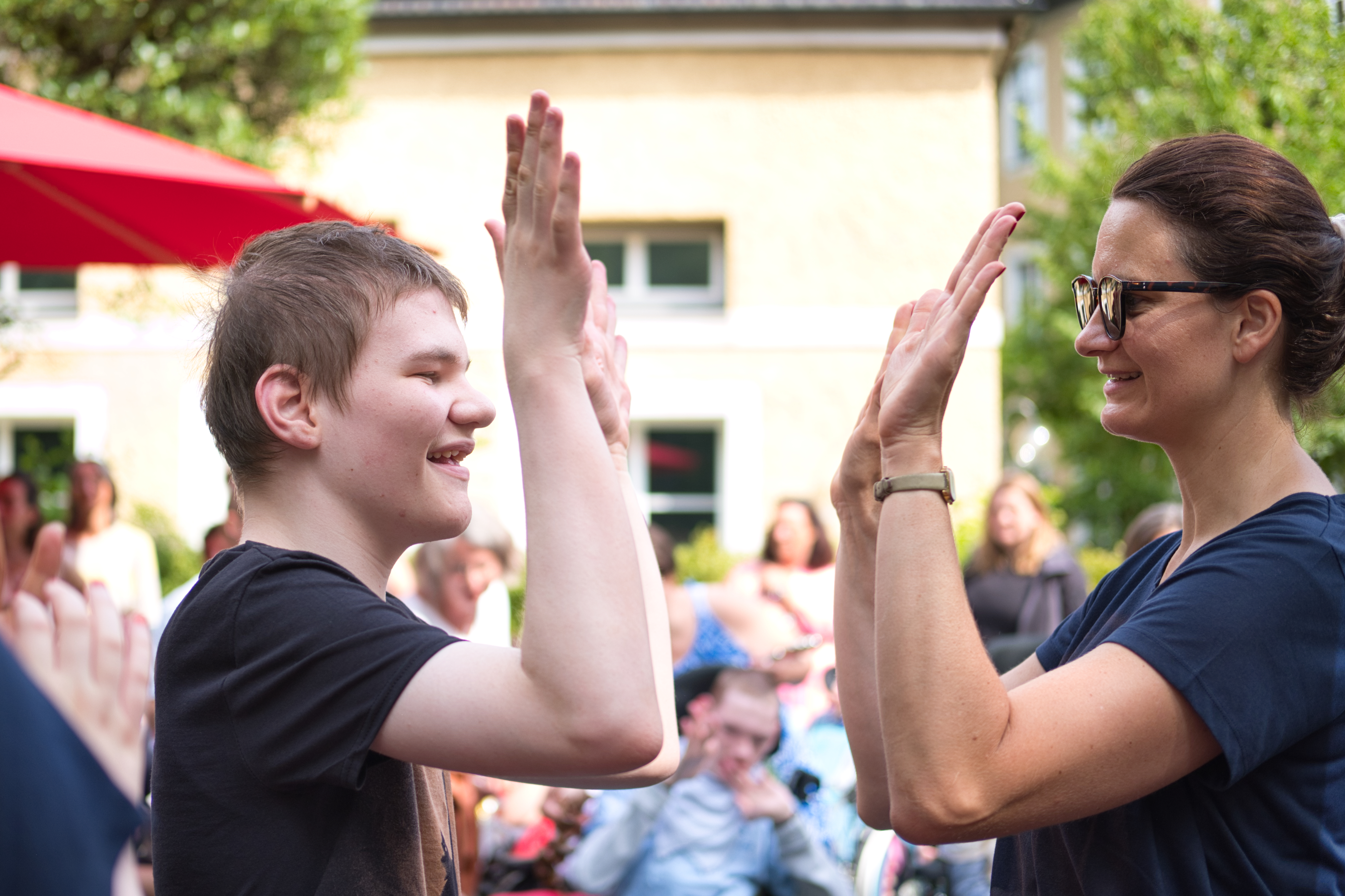 Auf dem Bild sieht man einen Jungen und seine Lehrerin, die sich abklatschen.