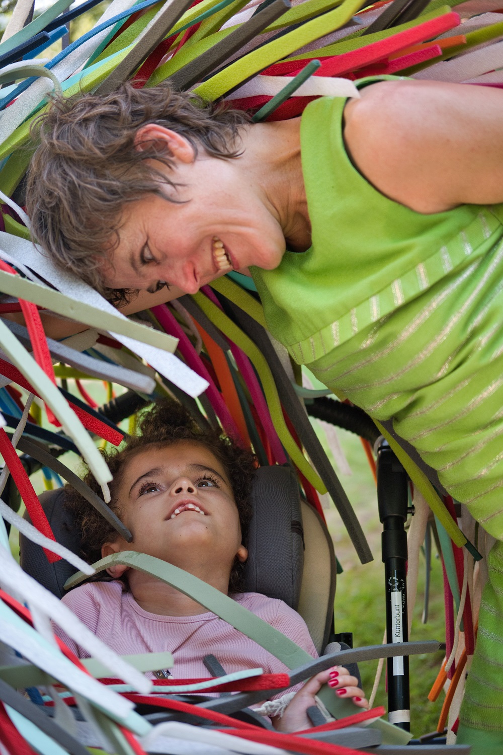 Das Bild zeigt ein Mädchen und eine Frau neben bunten Plastikschlangen.